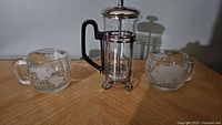 French press and two matching glass mugs displayed together