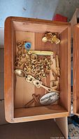 Interior view showing box contents: chain, cufflinks, tie clips, pocket knife, spoon, key fob and cross