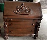 Front view of secretary desk showing carved panel and drawers
