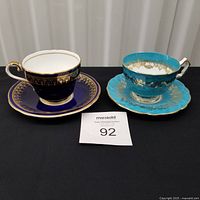 Both cup and saucer sets side by side on black surface
