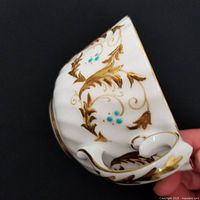 Close-up of cup side and handle showing gold scroll and turquoise enamel detail