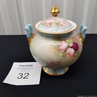 Front view of signed French porcelain jar with lid, floral design and handles