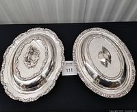 Both covered silver-plated entrée dishes side by side