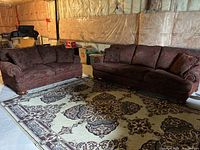 Sofa and loveseat side by side on a patterned carpet showing overall set condition and color.