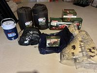 Full lot overview on basement floor showing jug, sacks, boxes and pillows