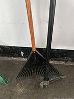 Front view showing the garden rake with wooden handle and black rake head alongside the weeder with black handle and metal head.