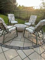 Four green metal chairs arranged around a fire pit (not included) on a patio, showing overall set.