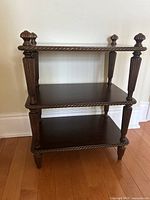 Front view of the three-tiered wooden shelf showing overall structure and dark brown finish.
