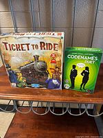 Photo showing the box covers of Ticket to Ride North America edition and Codenames Duet board games on a table.