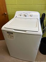 Front view of white top-loading washing machine with control panel and closed lid