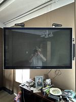 Front view of Toshiba 46-inch LCD TV on black stand in room, with reflection of person taking photo visible.