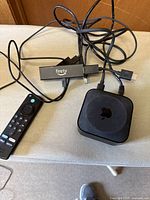 Photo showing Fire TV Stick with connected cables, Apple TV 3rd generation box with cables, placed on a flat surface.