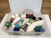 Overview of bin containing assorted yarn skeins and embroidery hoop