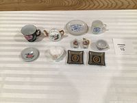 overall view of all eleven miniature porcelain and ceramic items arranged on striped cloth