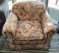 Front view of floral upholstered armchair with cushion in place