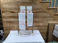Full view of gold towel rack with four embroidered towels displayed