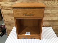 Front view showing full nightstand, drawer, open shelf, scalloped base
