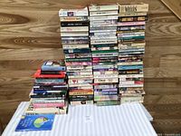 Two tall stacks of approximately 95 assorted books on table