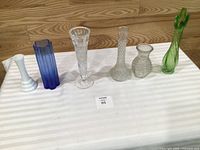 Six bud vases lined up on table