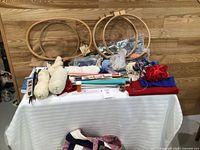 Overall lot on table showing hoops, yarn, needles, fabric, threads, tote