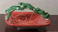 Photo of Fitz and Floyd ceramic dish with red interior and three green frogs forming the handle