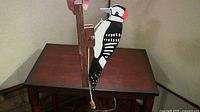 Full side view of the woodpecker door knocker showing the painted woodpecker and wooden mount.