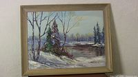 Framed oil painting showing landscape with snow, trees, and water.