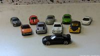 Photo showing 10 Hot Wheels diecast cars in assorted colors and models, some with roof details and various paint finishes.