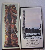 Two framed art prints hanging side by side on a wall; left print shows carved Haida totem profiles, right print is the Roy Henry Vickers gallery poster.