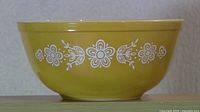 Front view of vintage Pyrex mixing bowl showing Butterfly Gold pattern in white floral motifs on golden yellow glass.