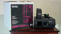 Vivitar 5000AF slide projector with round carousel on top and original box beside it