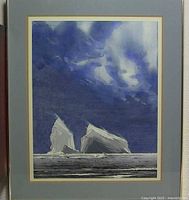 Full view of framed watercolor painting showing two icebergs in seascape with dramatic sky.