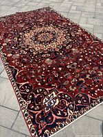 Angled full view of the rug laid on stone patio showing overall pattern and condition