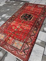 Full view of rectangular red wool rug laid on stone patio