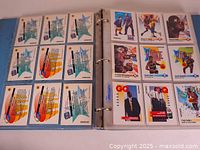 Photo of binder open to reveal basketball cards organized in plastic sleeves, including multiple cards featuring Michael Jordan and other players from the 1991 SkyBox set.