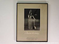 Full view of framed black and white photo showing the tulip drooping and clear glass vase, mounted with a beige matte including printed gallery information and signature.