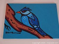 Front view of small canvas painting depicting a stylized blue jay on a branch with clear view of artist signature