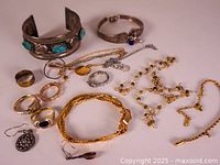 Overview of the lot's jewelry items on flat surface showcasing bracelets, rings, necklaces, and earrings.