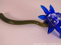 Close-up side view of blue glass flower with green stem showing hand-blown detail.