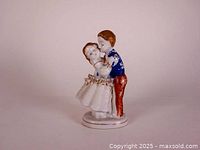 Overall view of colonial couple figurine showing front and side profile with painted details and fabric lace skirt trim.