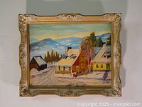 Full view of a framed winter landscape painting showing snow-covered houses and a mountain background.