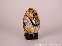 Front view of the vintage Satsuma egg on its stand, showing detailed gold and painted decorative motif.