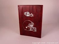 Front cover of the maroon Classic brand sports card binder with a white graphic of a football helmet.