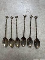 Six silver plated teaspoons laid out with teapot-shaped handles visible, showing the textured bamboo-like handle design.