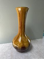 Front view of tall harvest gold glazed vase with bulbous base and narrow neck.