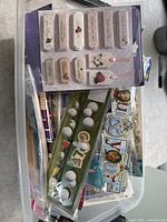 Various sticker sheets and embellishments packed together in a tote bag with visible golf ball themed stickers, floral and heart-shaped tags.