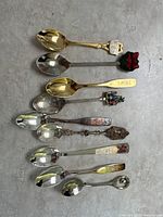 Full view of nine silver plated spoons with various Christmas and Disneyland themes arranged in a row.