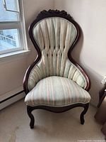 Front view of Victorian-style upholstered accent chair showing striped upholstery and carved wooden frame.