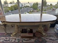 Photo showing the top of the solid wood dining table with two leaves extended, polished surface and carved edges.