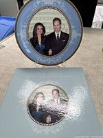 Photo of the front side of the commemorative plate showing Prince William and Catherine Middleton with a blue patterned border and original box.